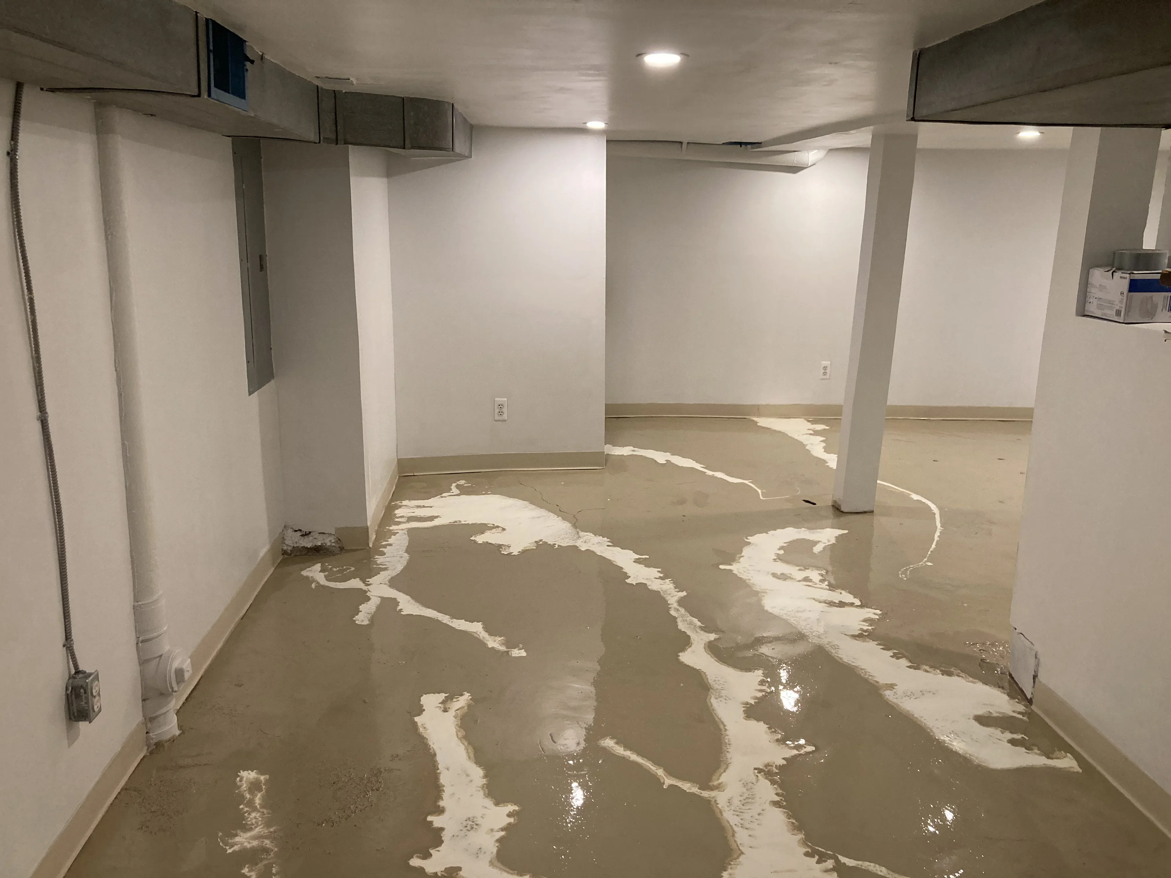 Basement concrete floor with white epoxy striping pattern and support columns
