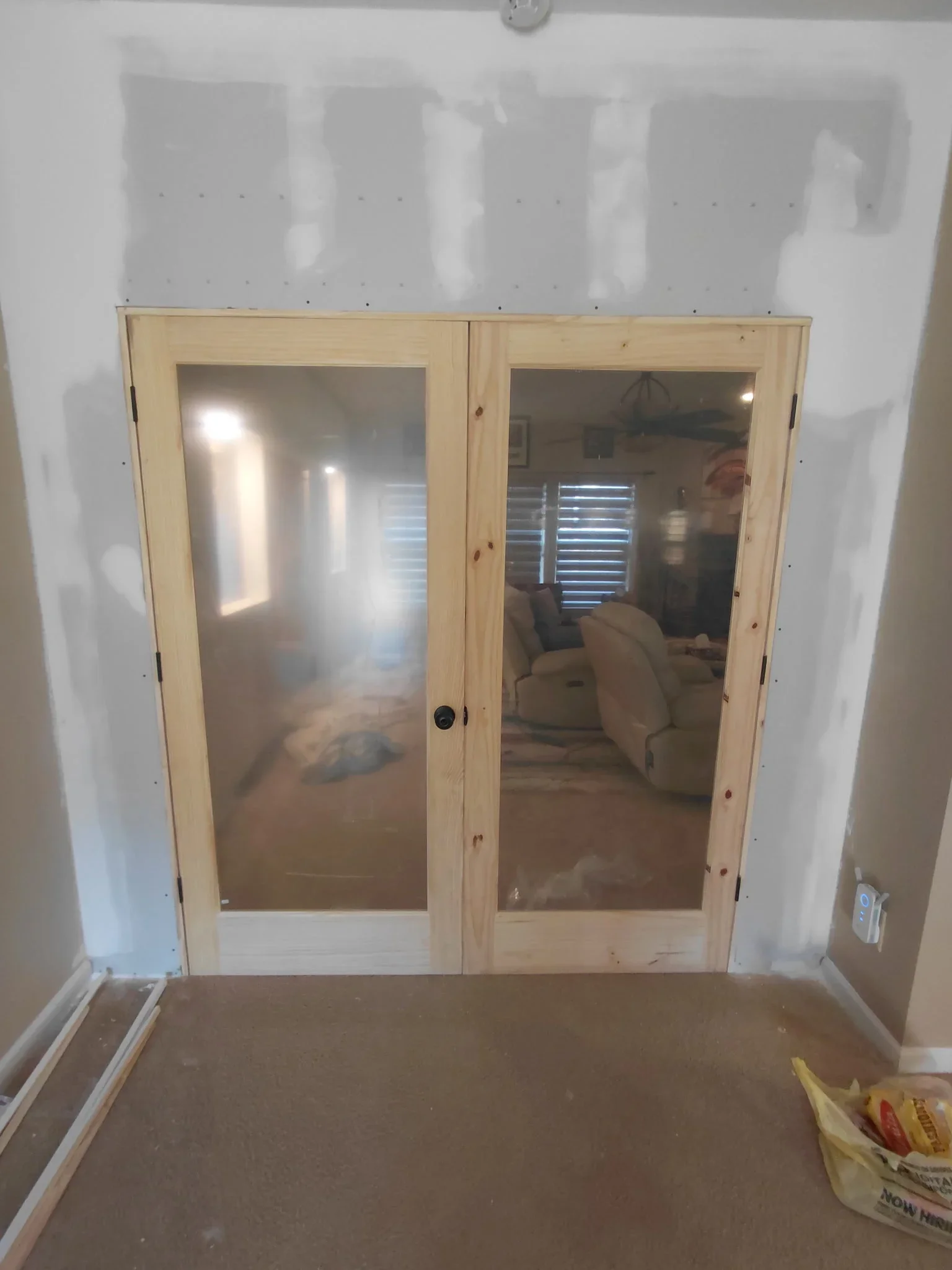 Two pine French doors with glass panels installed in interior wall opening