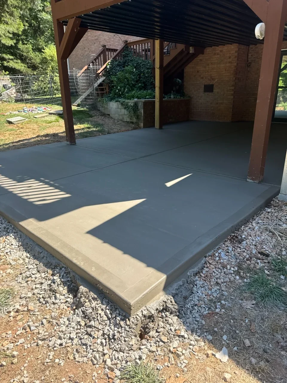Finished concrete patio slab with concrete border under timber pergola structure