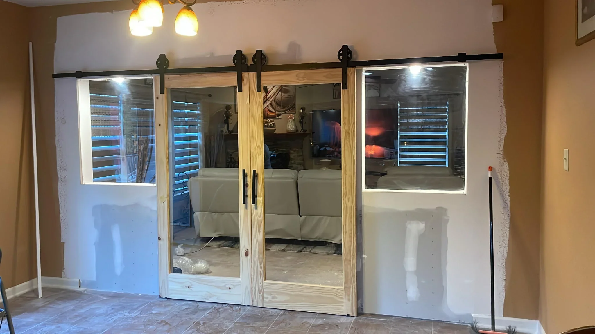 Three-panel sliding barn door with glass and wood frames, black metal hardware and track system