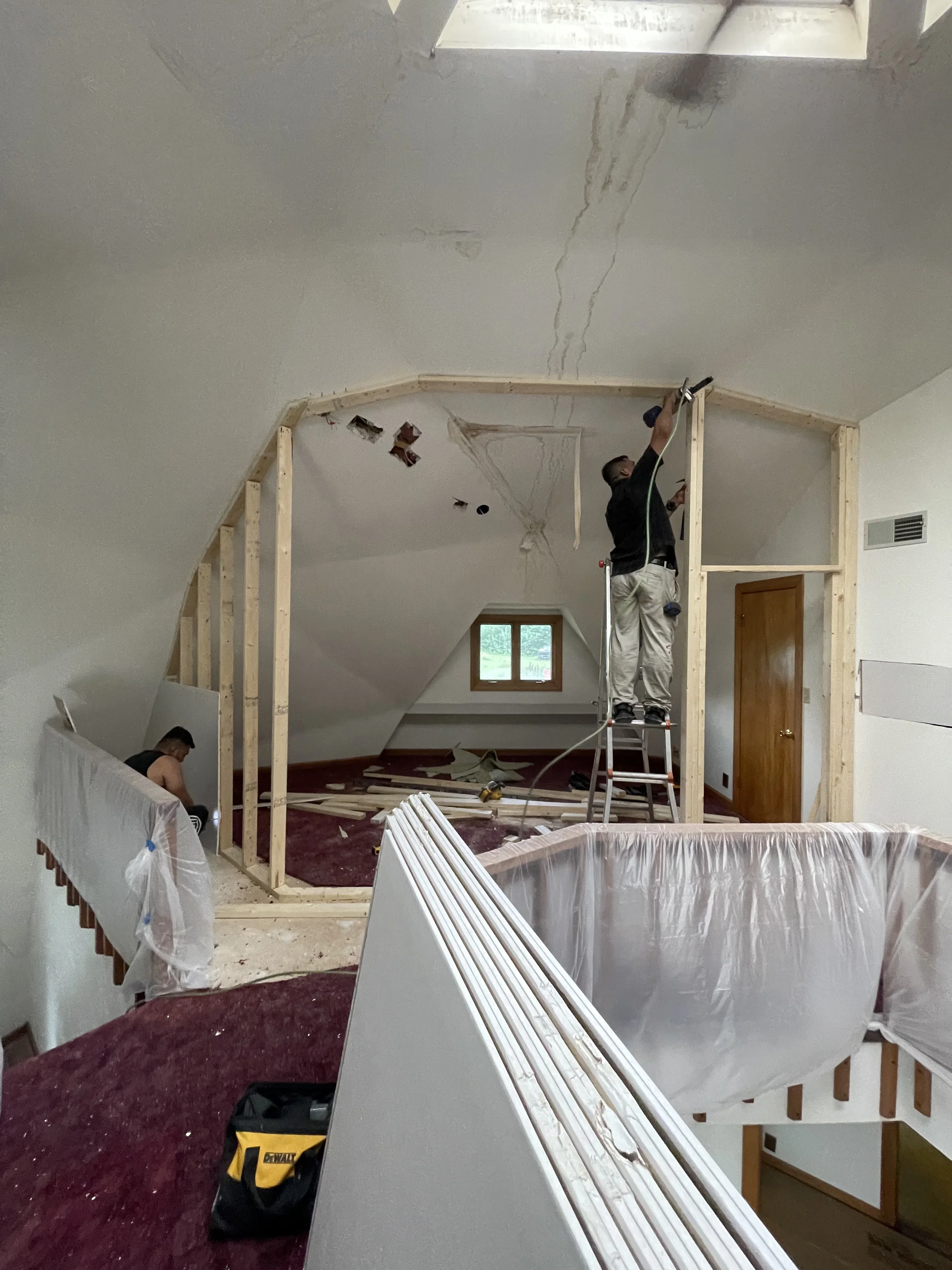 Attic framing with wood studs and drywall installation in progress