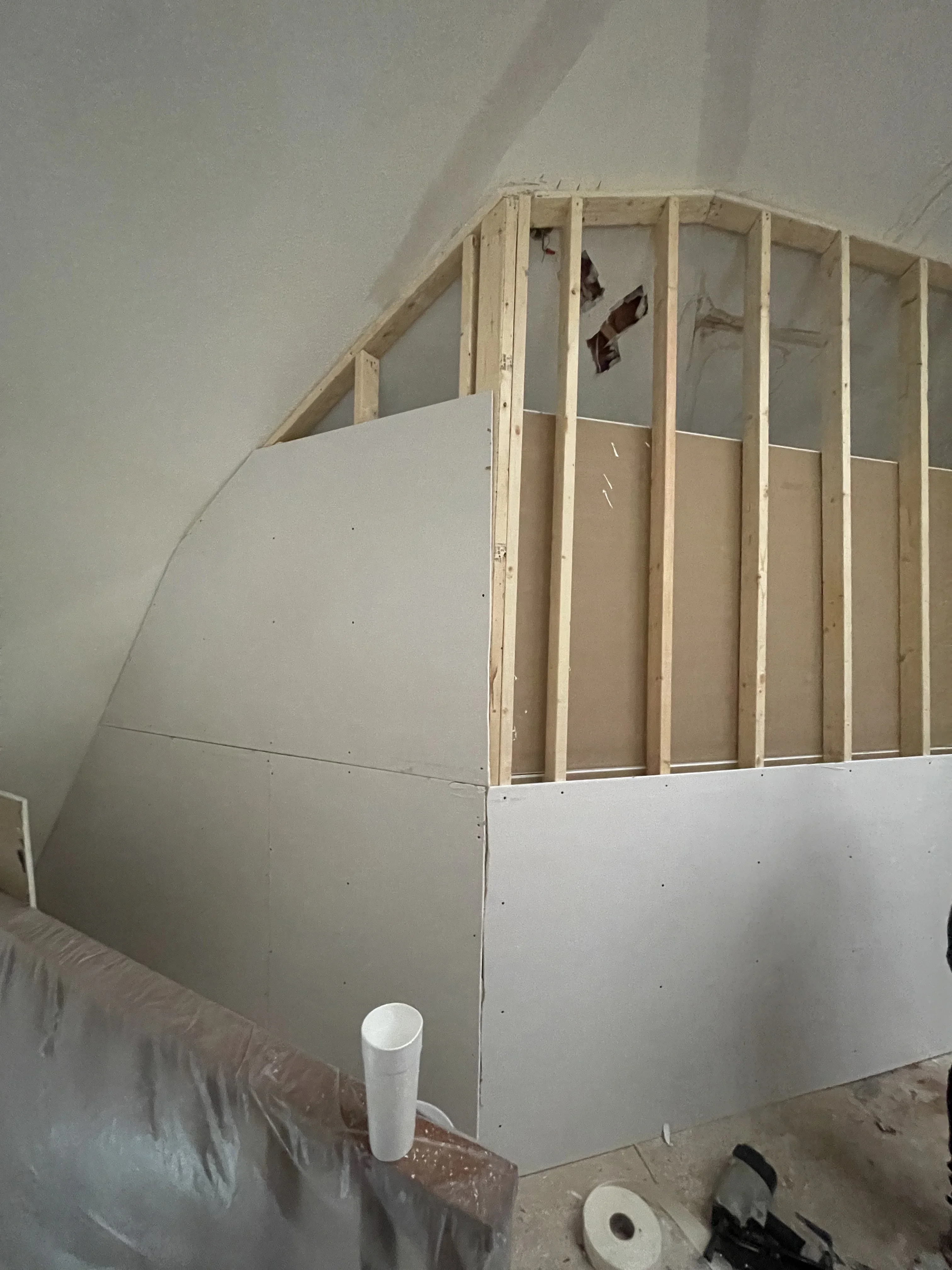 Attic framing with wood studs and drywall installation on sloped ceiling