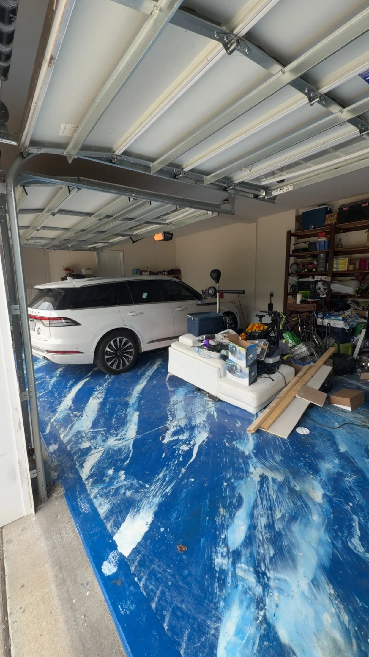 White aluminum ceiling beams with metal brackets and blue epoxy garage floor
