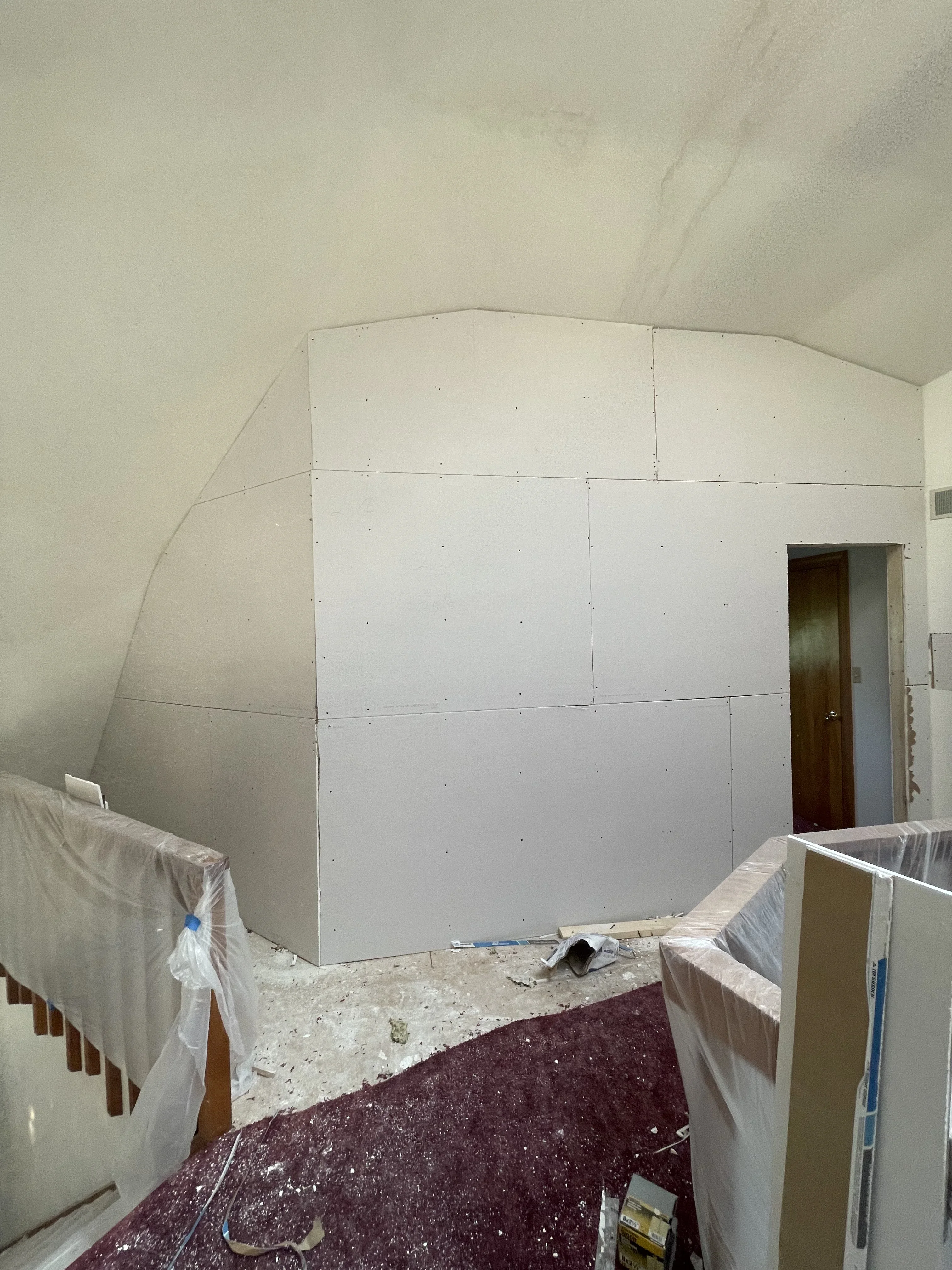 Drywall sheets installed on curved interior walls with visible seams and fasteners