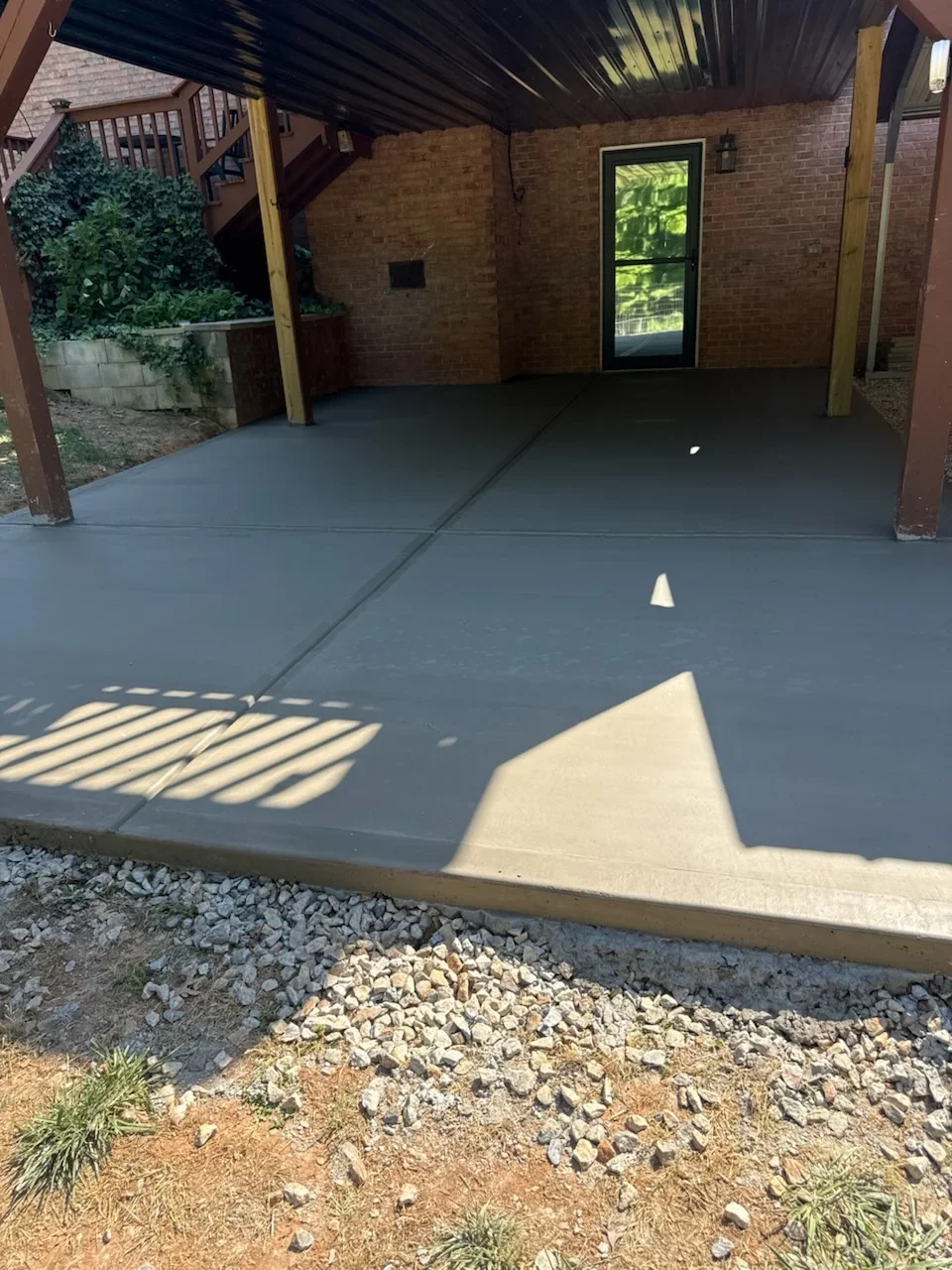 Newly poured concrete carport and patio with control joints, brick walls, and wooden support posts
